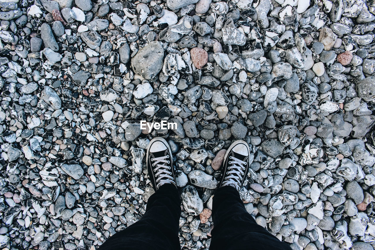 LOW SECTION OF MAN STANDING WITH PEBBLES