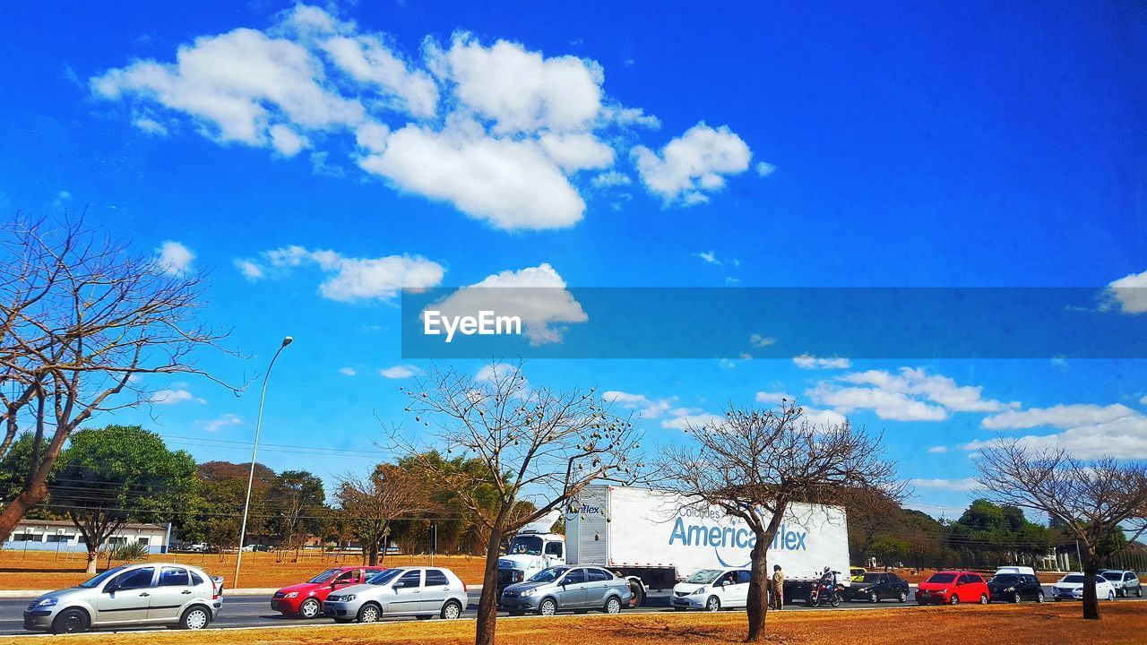 CARS PARKED ON ROAD AGAINST CLOUDY SKY