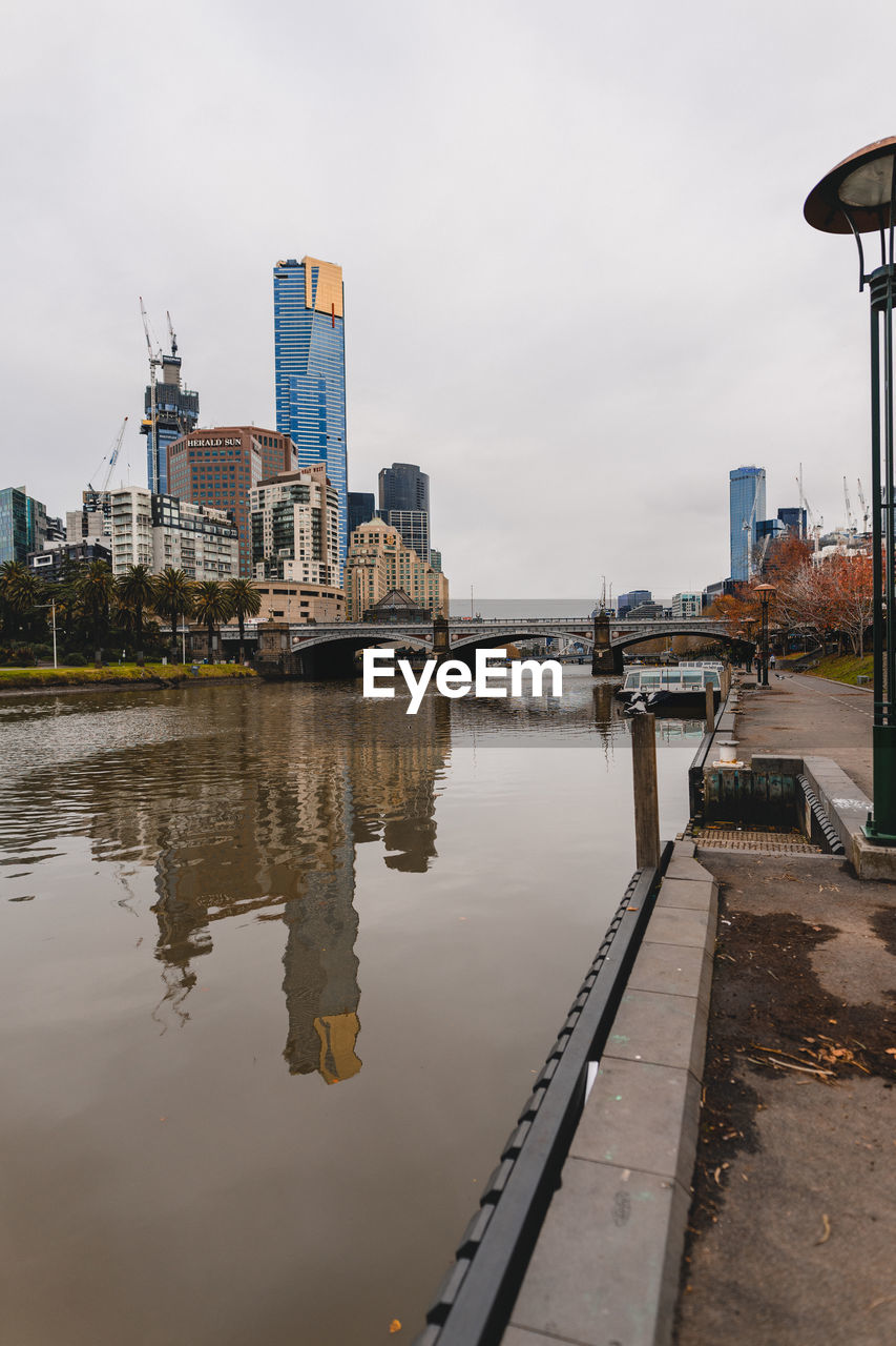 Buildings by river against sky in city, melbourne,