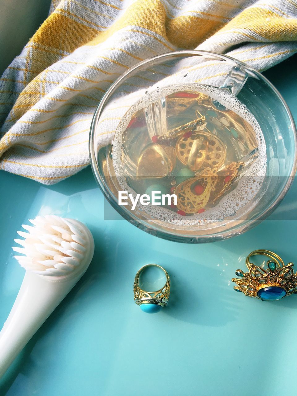 High angle view of jewelries in bowl and brush on table