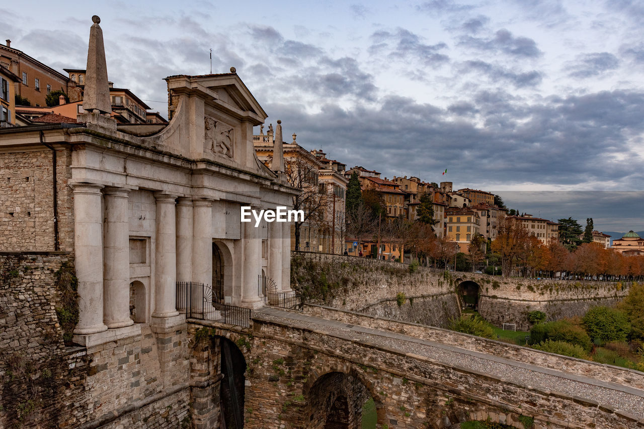 Low angle view of old building against cloudy sky, porta san giacomo in bergamo