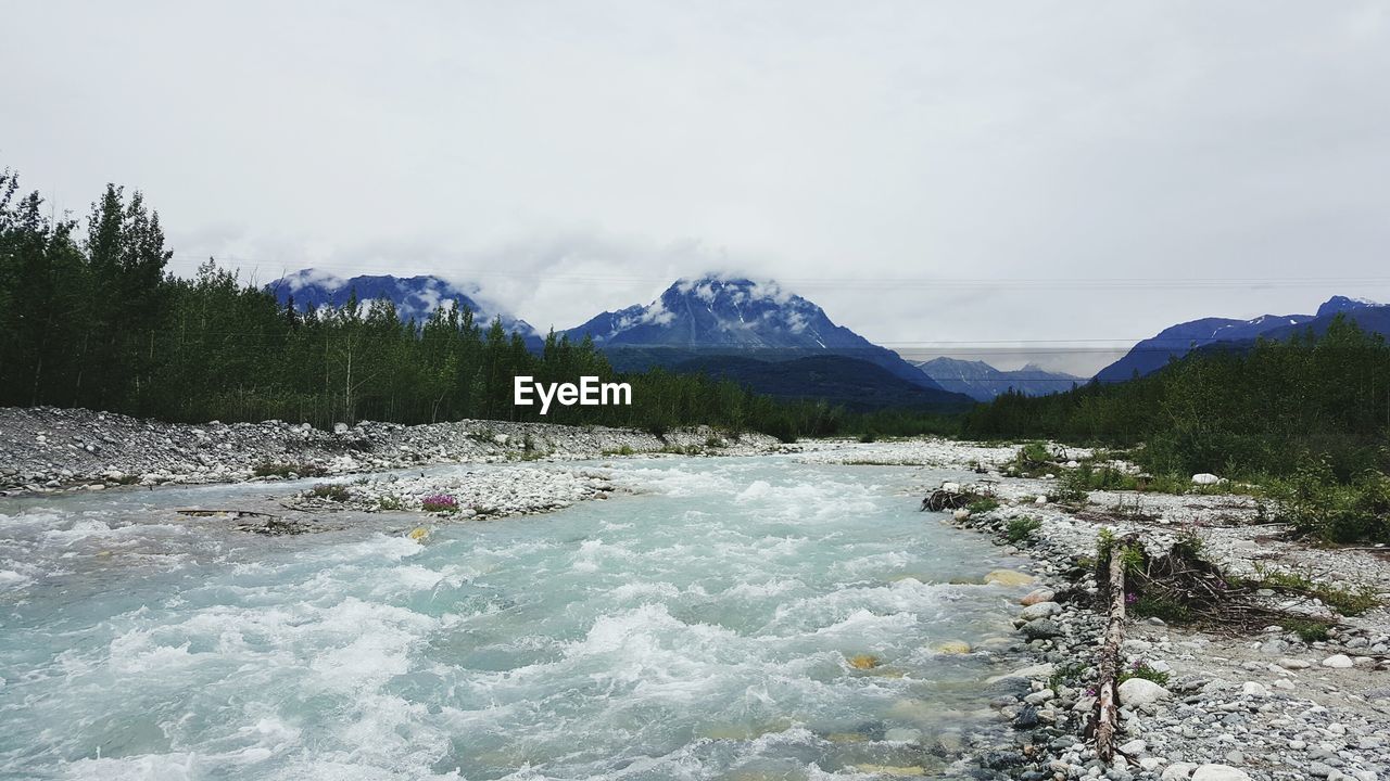 Scenic view of river by mountains against sky