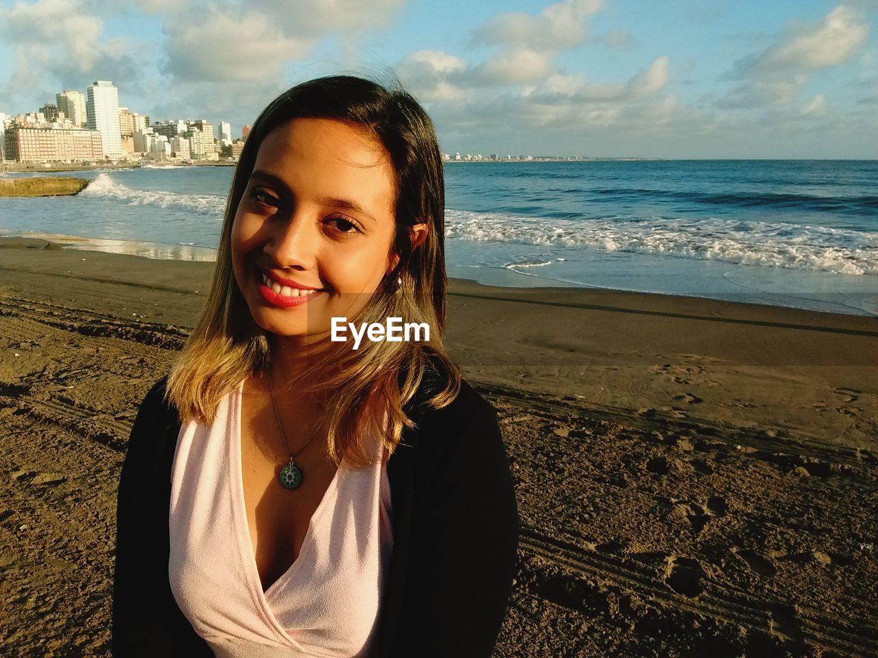 PORTRAIT OF SMILING YOUNG WOMAN AT BEACH