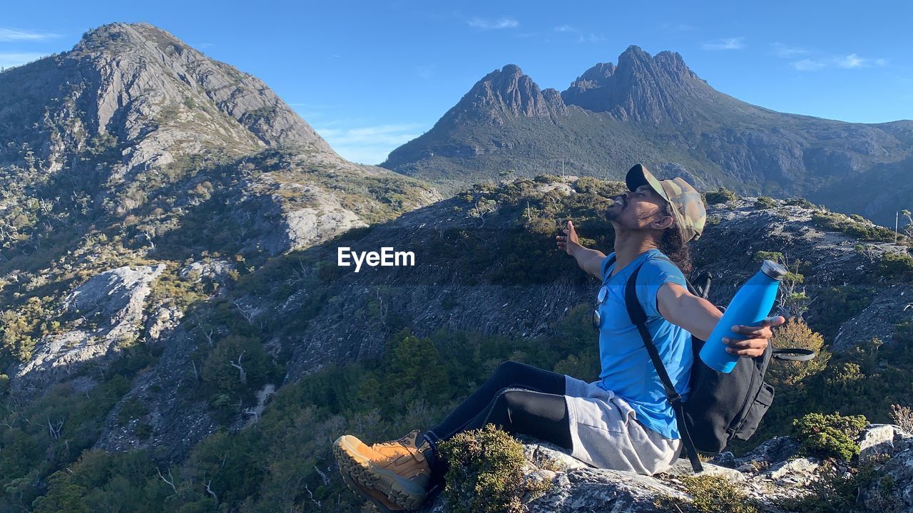 Woman sitting on rock against mountains