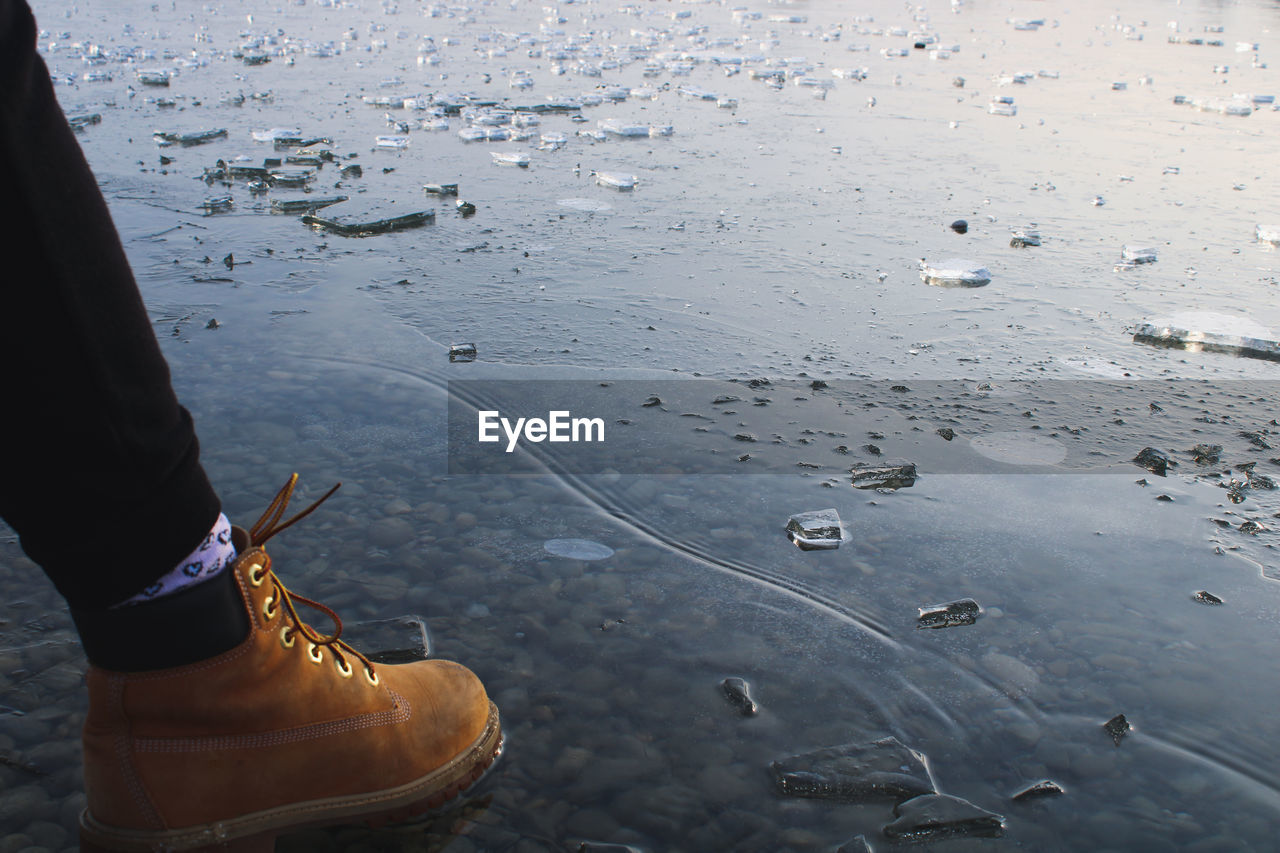 LOW SECTION OF WOMAN STANDING BY WATER