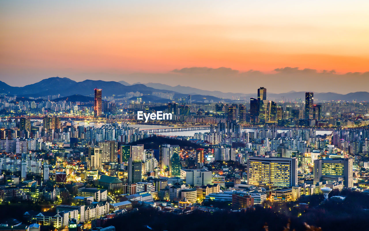 High angle view of illuminated cityscape against sky at dusk