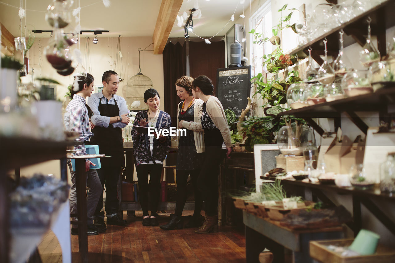 Owner explaining workers through tablet computer in plant shop