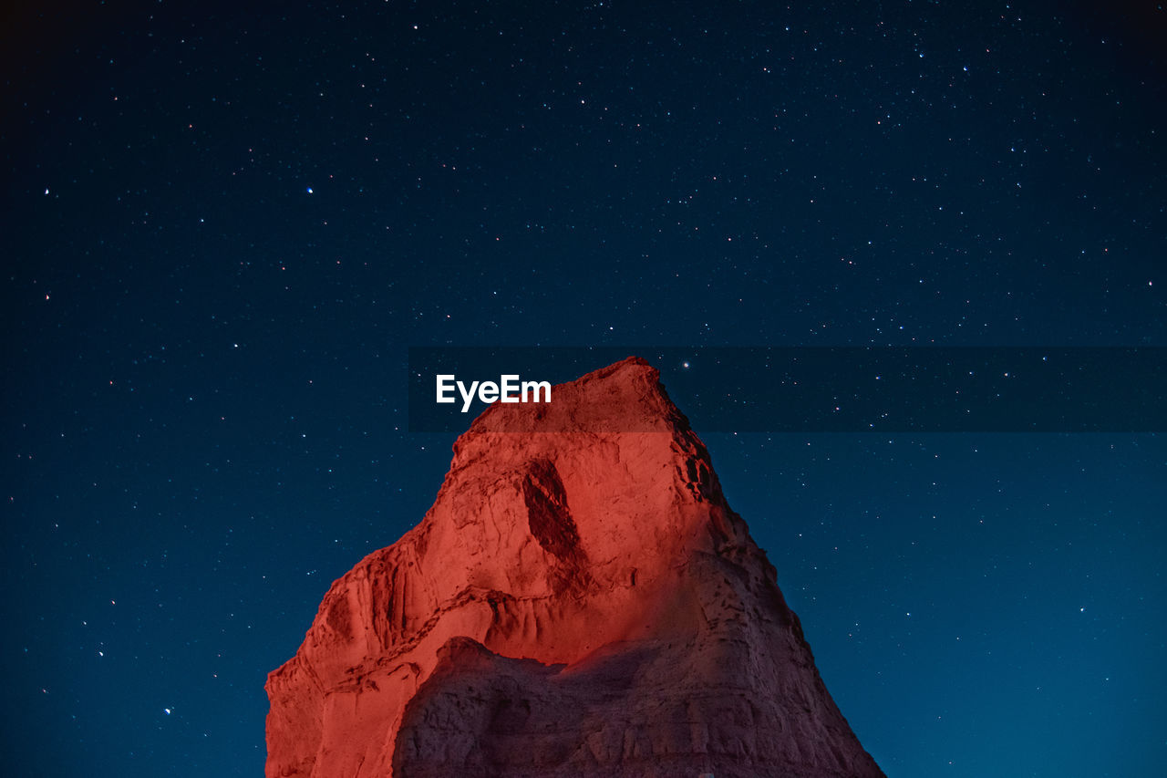 Low angle view of star field and a mountain against sky at night