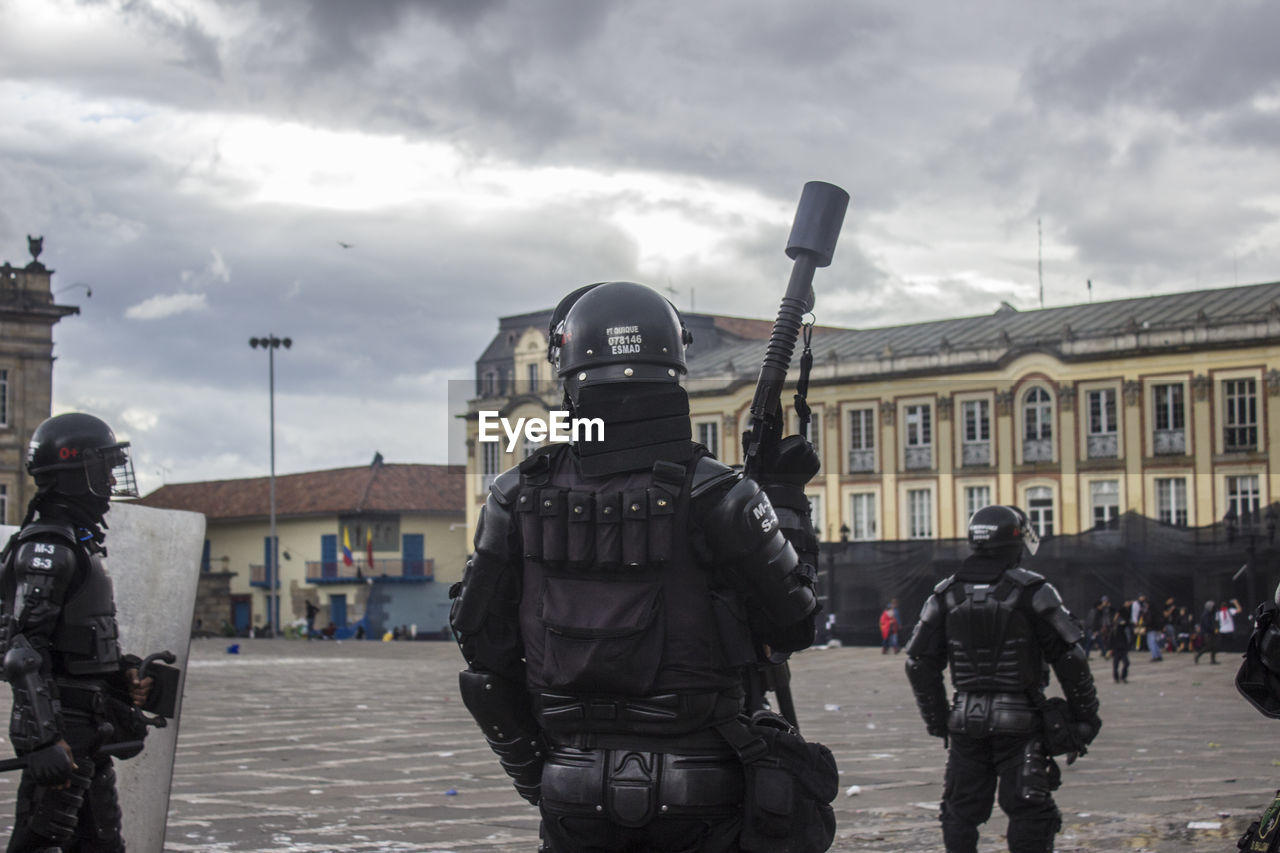 Police force guarding on street against cloudy sky