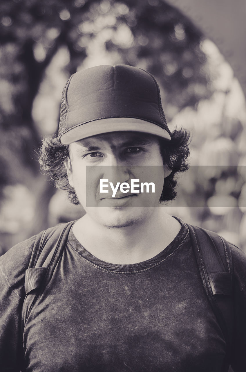 PORTRAIT OF YOUNG MAN STANDING AGAINST HAT