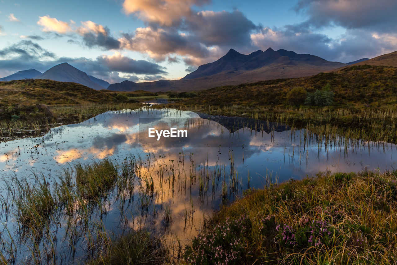 Scenic view of lake and mountains against dramatic sky