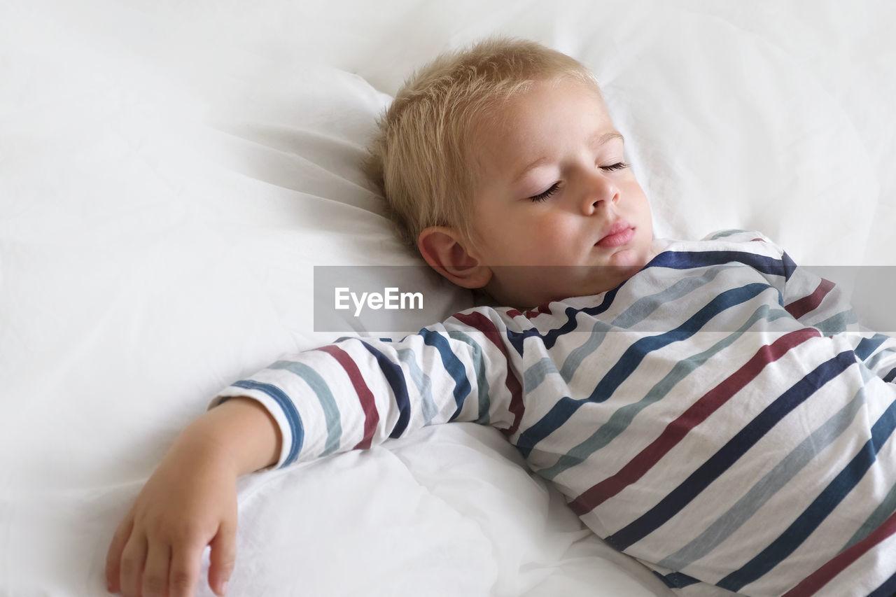 high angle view of cute baby boy sleeping on bed at home