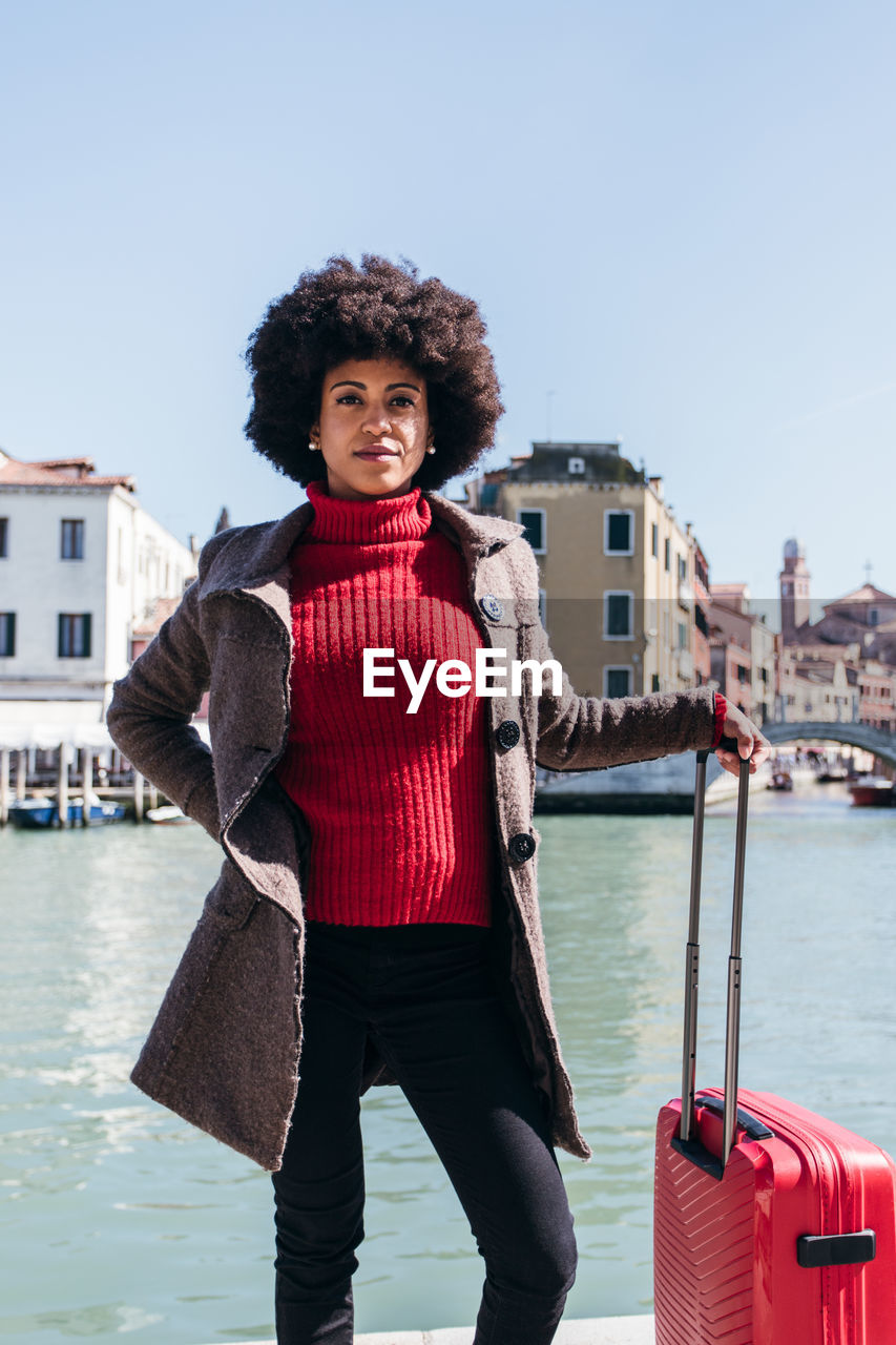 Young black woman holding luggage travel bag