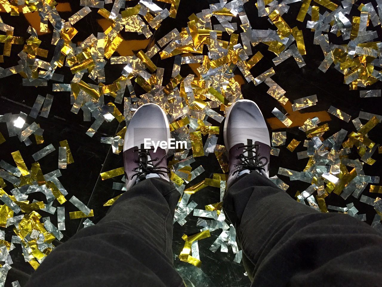 Low section of man standing on floor covered with confetti