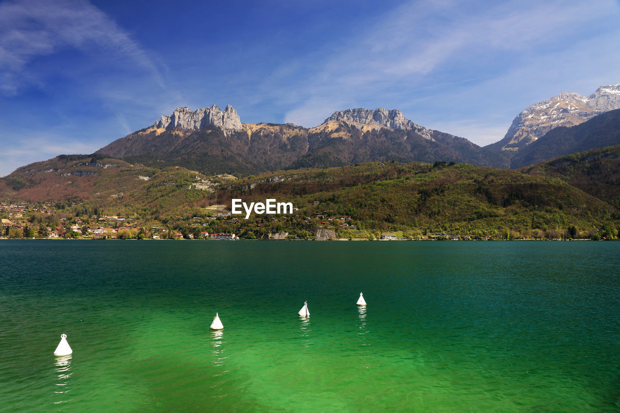 SWANS SWIMMING ON LAKE AGAINST MOUNTAIN RANGE