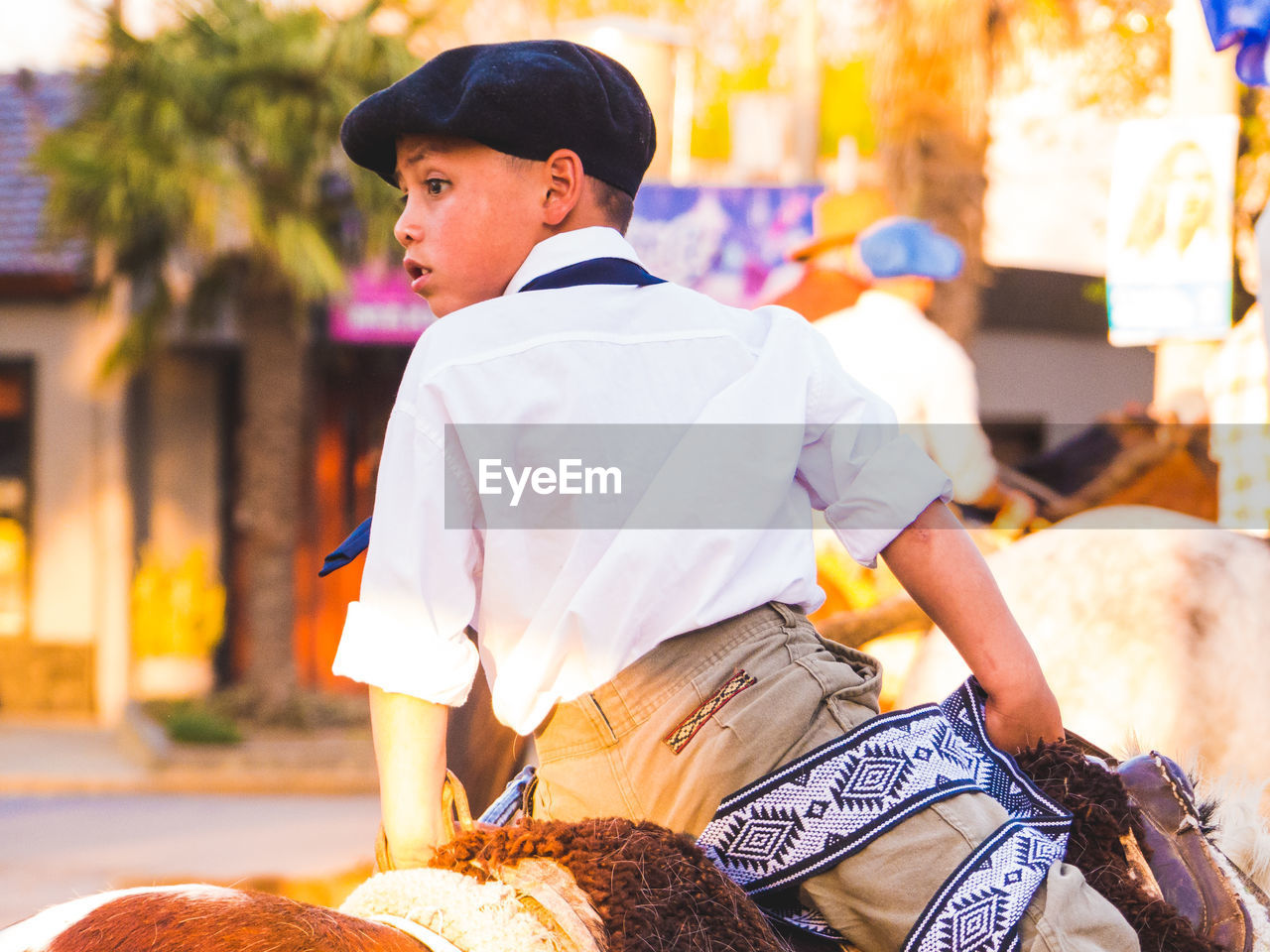 Rear view of boy riding horse in city