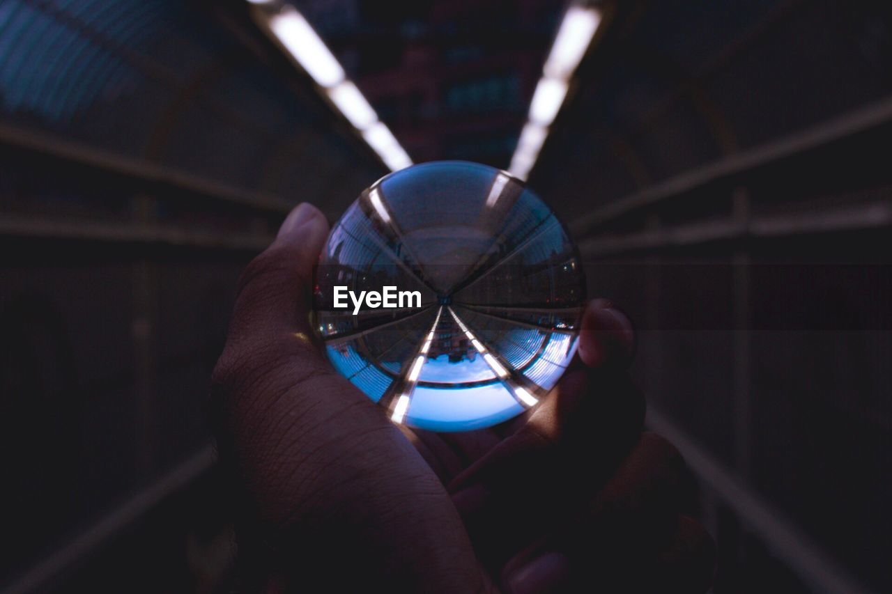 Cropped image of hand holding crystal ball in tunnel