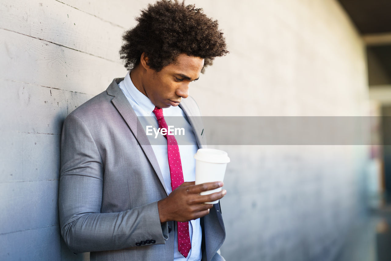 PORTRAIT OF YOUNG MAN DRINKING COFFEE IN CUP