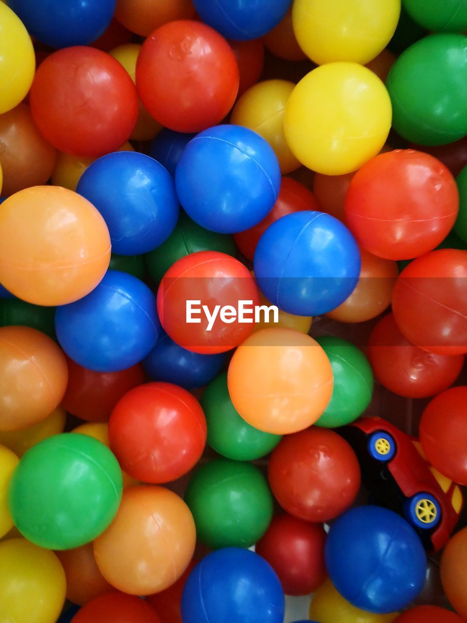 HIGH ANGLE VIEW OF MULTI COLORED BALLS IN BLUE CONTAINER