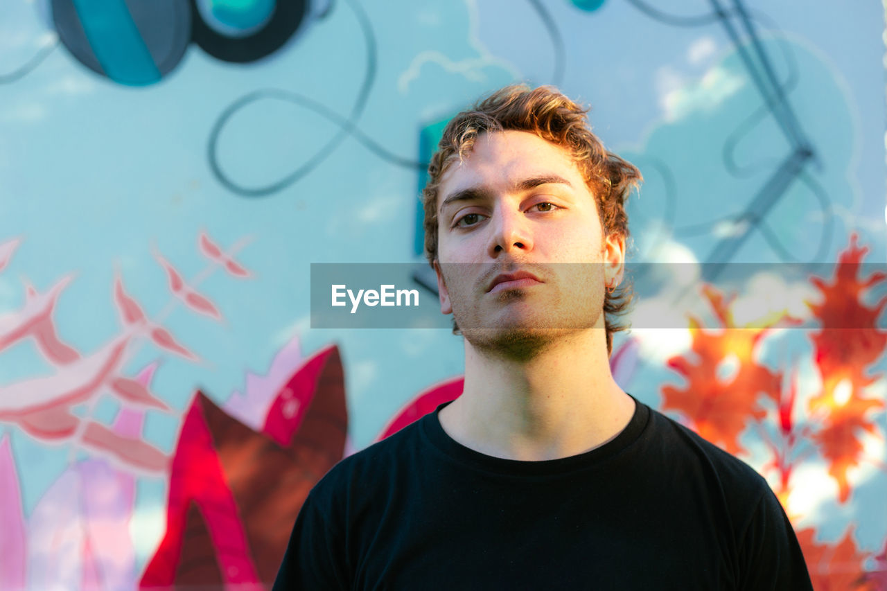 A young white man with a serious face expression. colorful background.