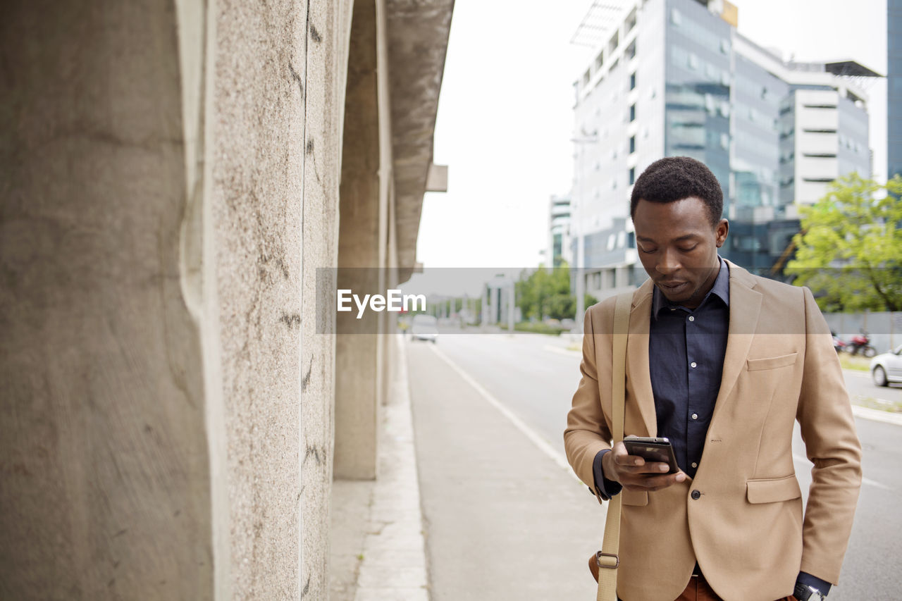 Businessman using smart phone on city street