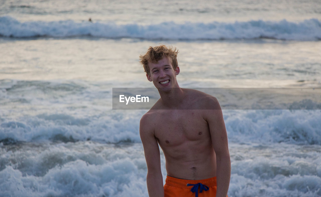 Portrait of shirtless young man at beach