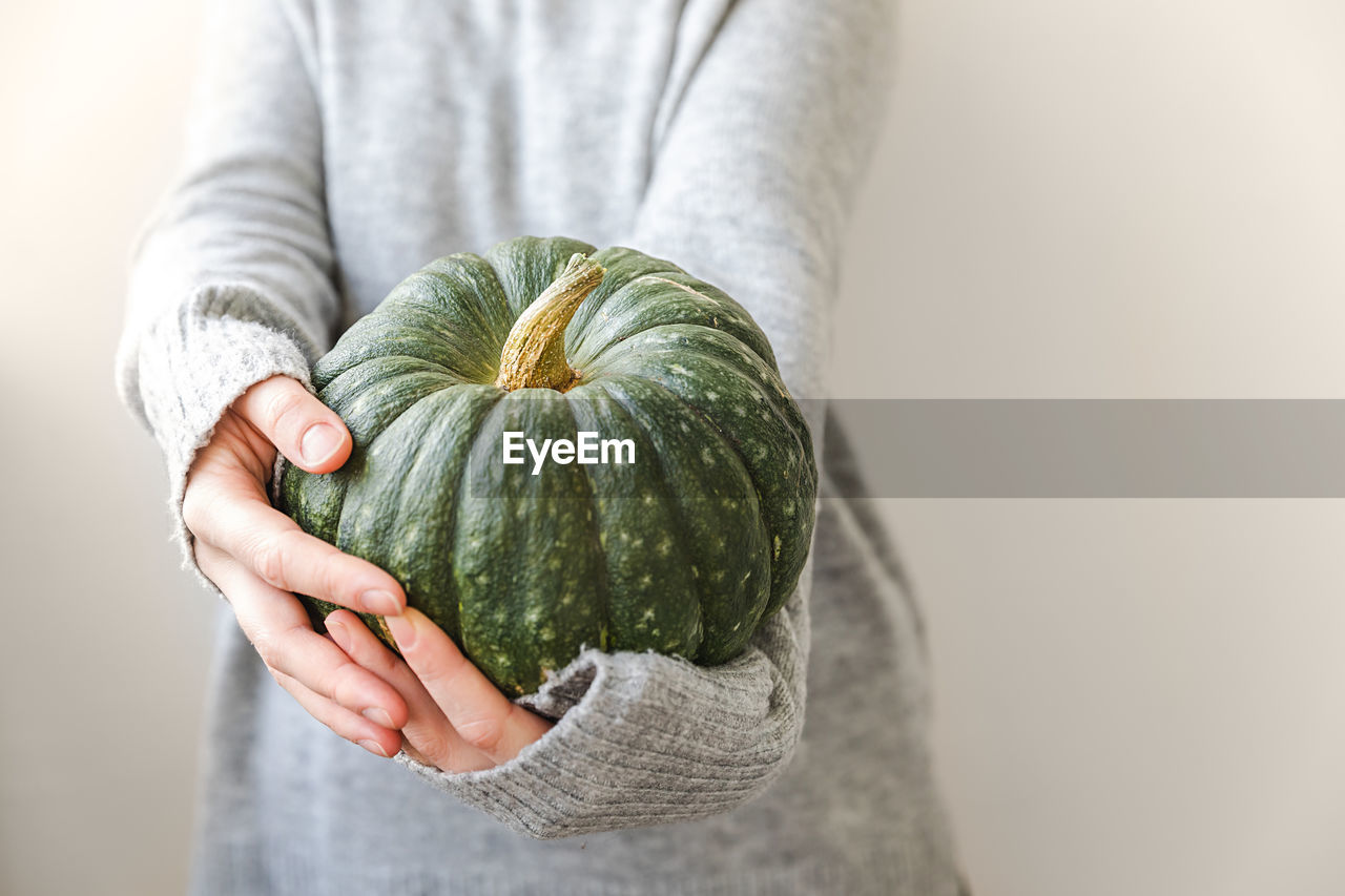 midsection of woman holding pumpkin at home
