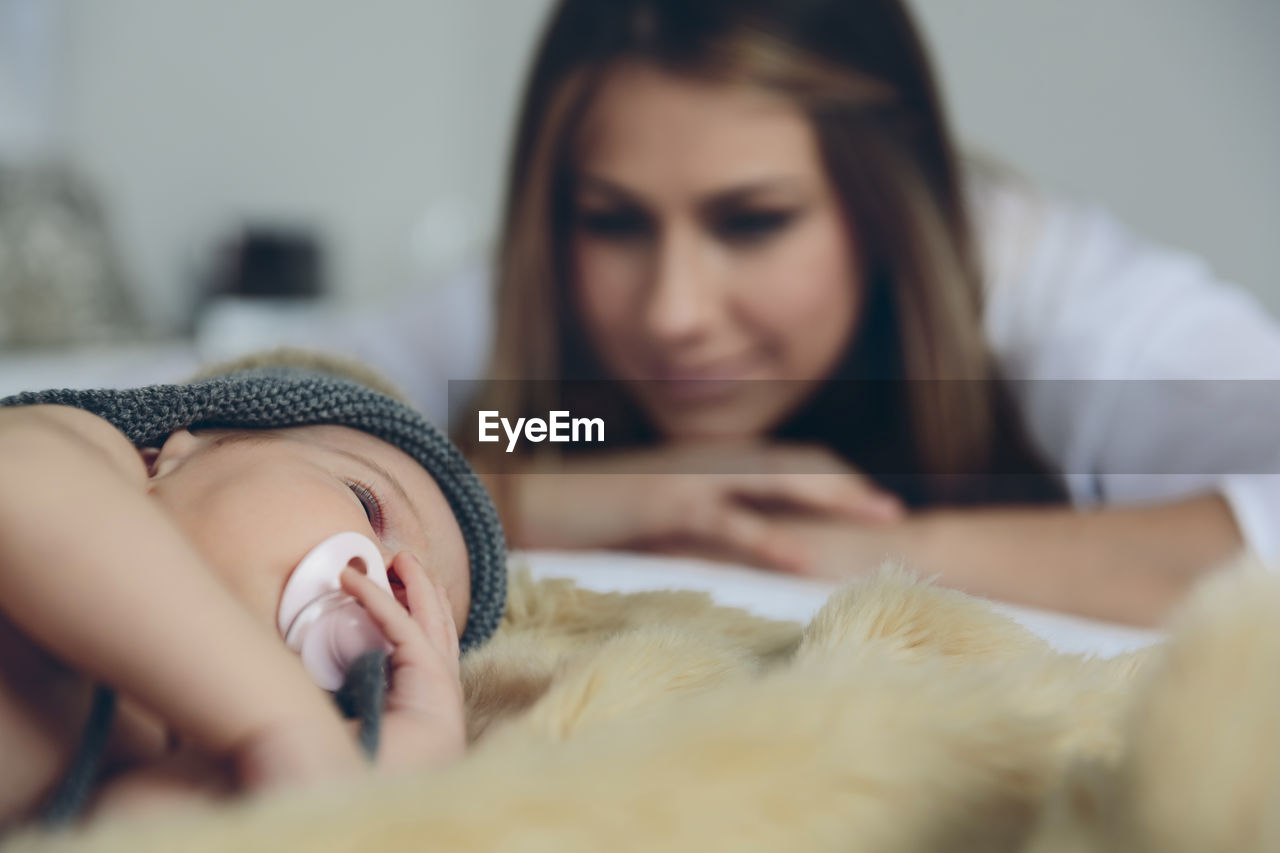 Mother looking at sleeping daughter on bed at home