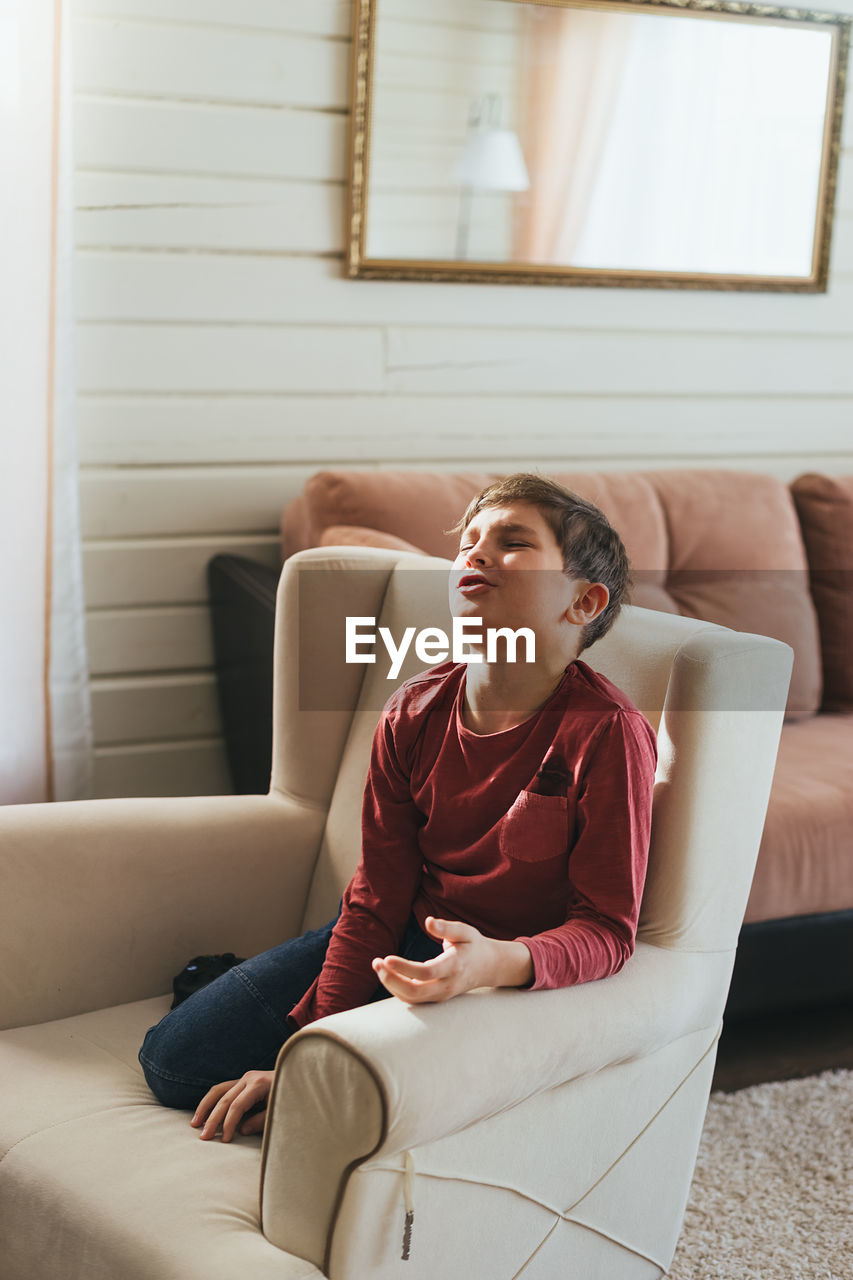 Full length of boy sitting on sofa at home