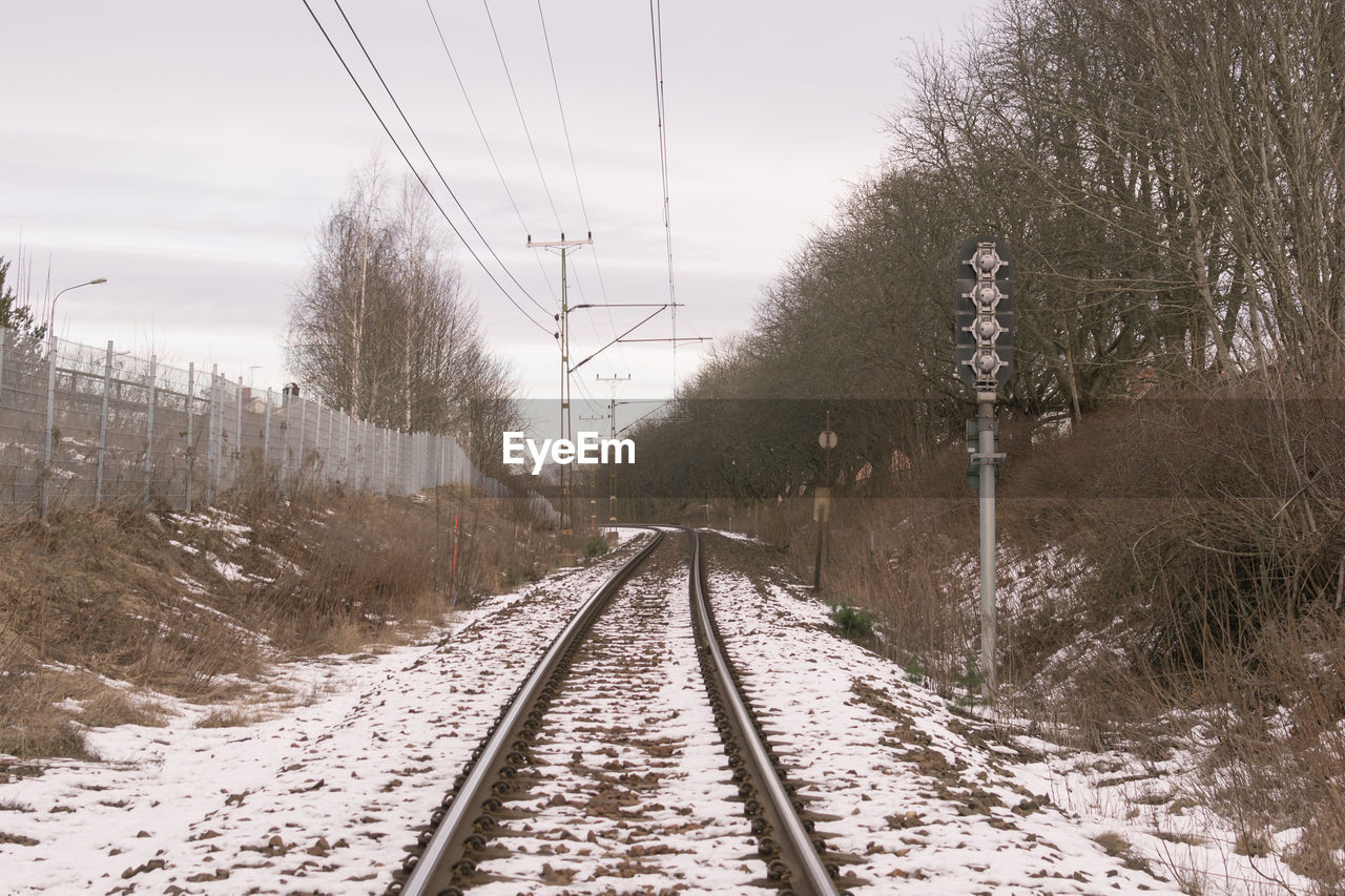 RAILROAD TRACKS ON SNOW COVERED LANDSCAPE