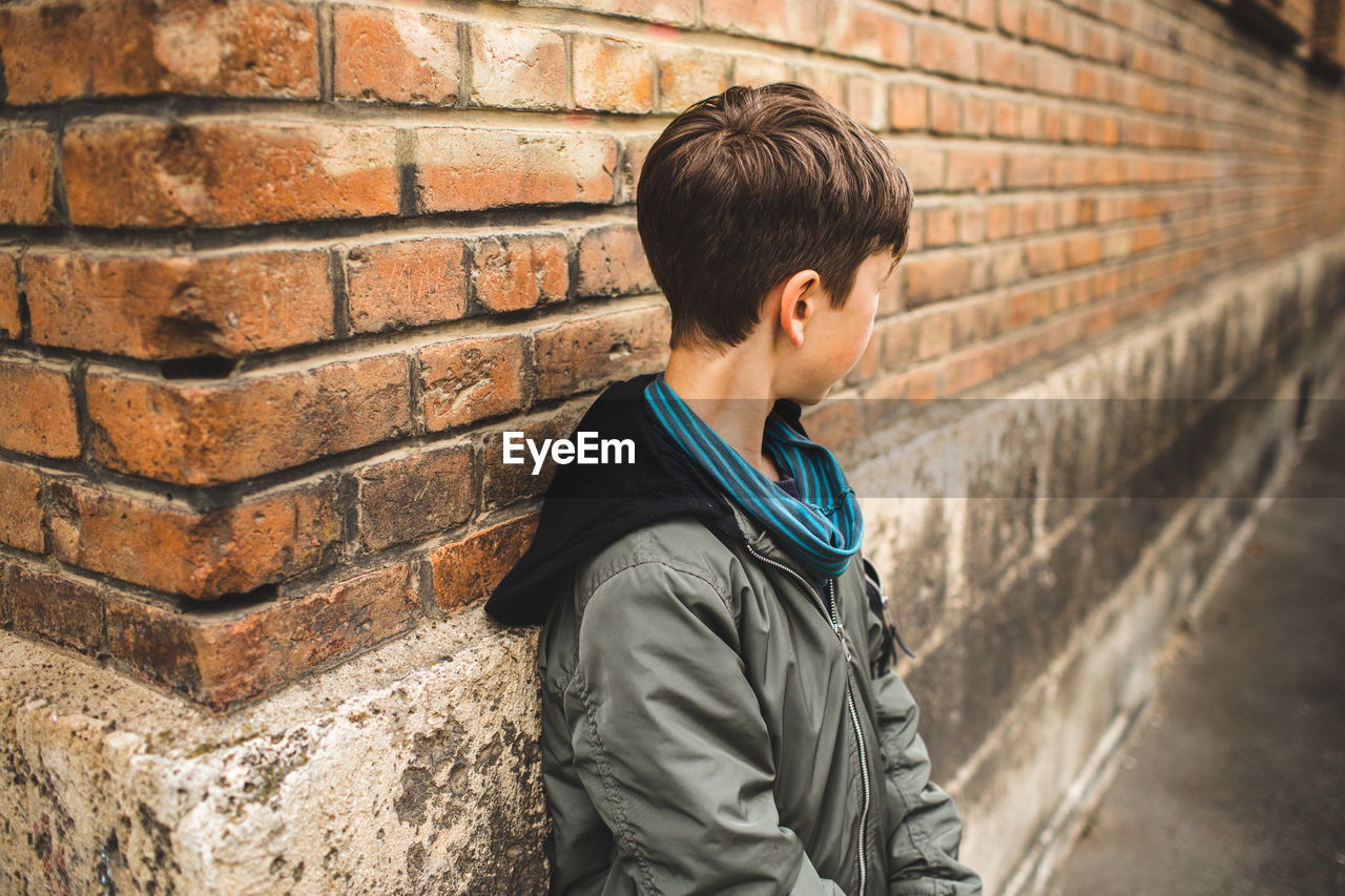 Side view of boy standing against wall