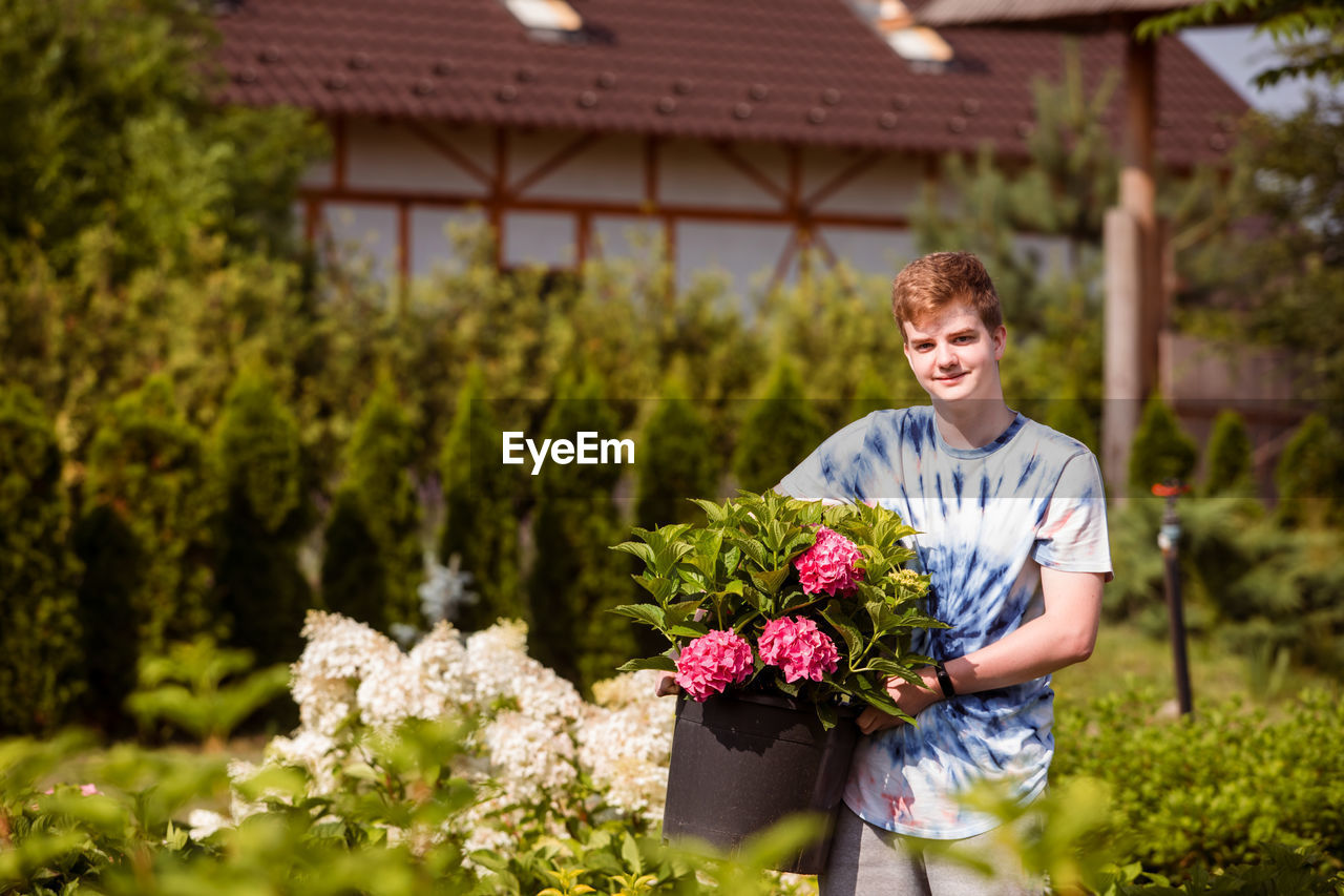 Portrait of boy holding flowers while standing on field