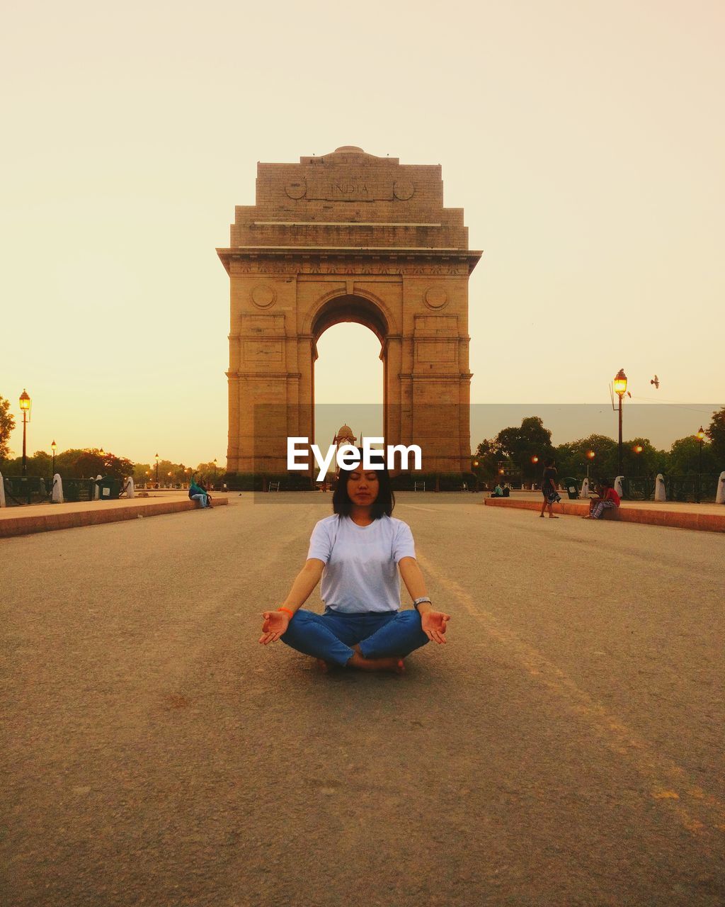 Full length of woman doing yoga while sitting in city against sky