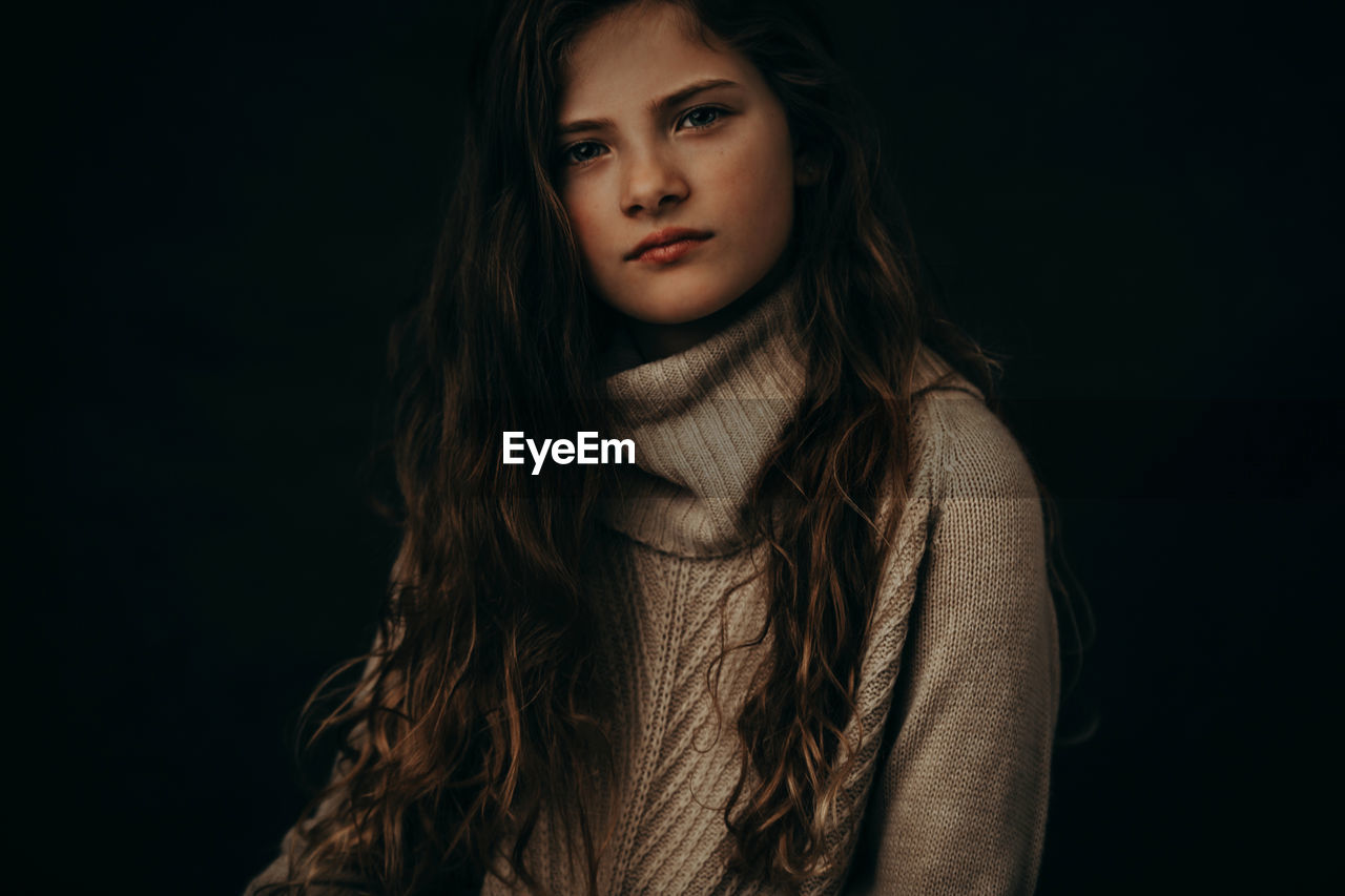 Portrait of cute girl against black background