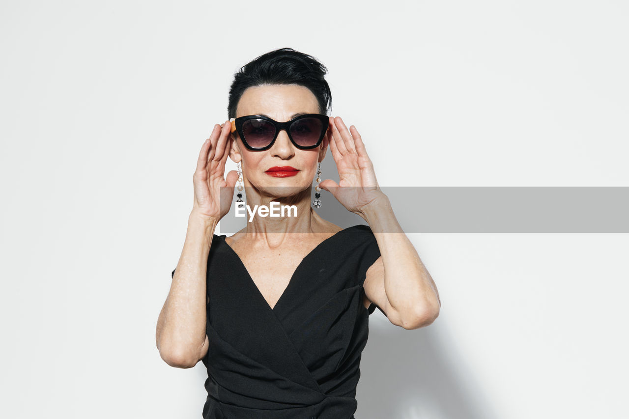 portrait of woman wearing sunglasses against white background