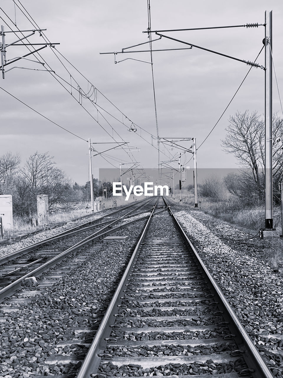 railroad track, track, rail transportation, transportation, transport, cable, electricity, railway, line, electricity pylon, black and white, sky, power line, mode of transportation, the way forward, power supply, nature, monochrome, vanishing point, no people, technology, vehicle, diminishing perspective, public transportation, monochrome photography, lane, architecture, tree, travel, day, cloud, train station, parallel, outdoors, residential area, straight, railroad station