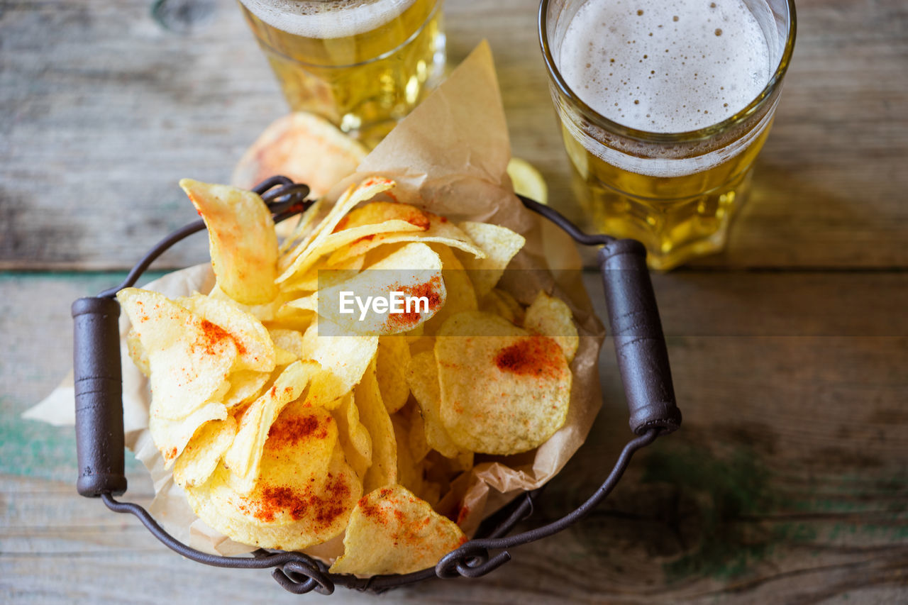 High angle view of fresh crunchy potato chips with beer on table