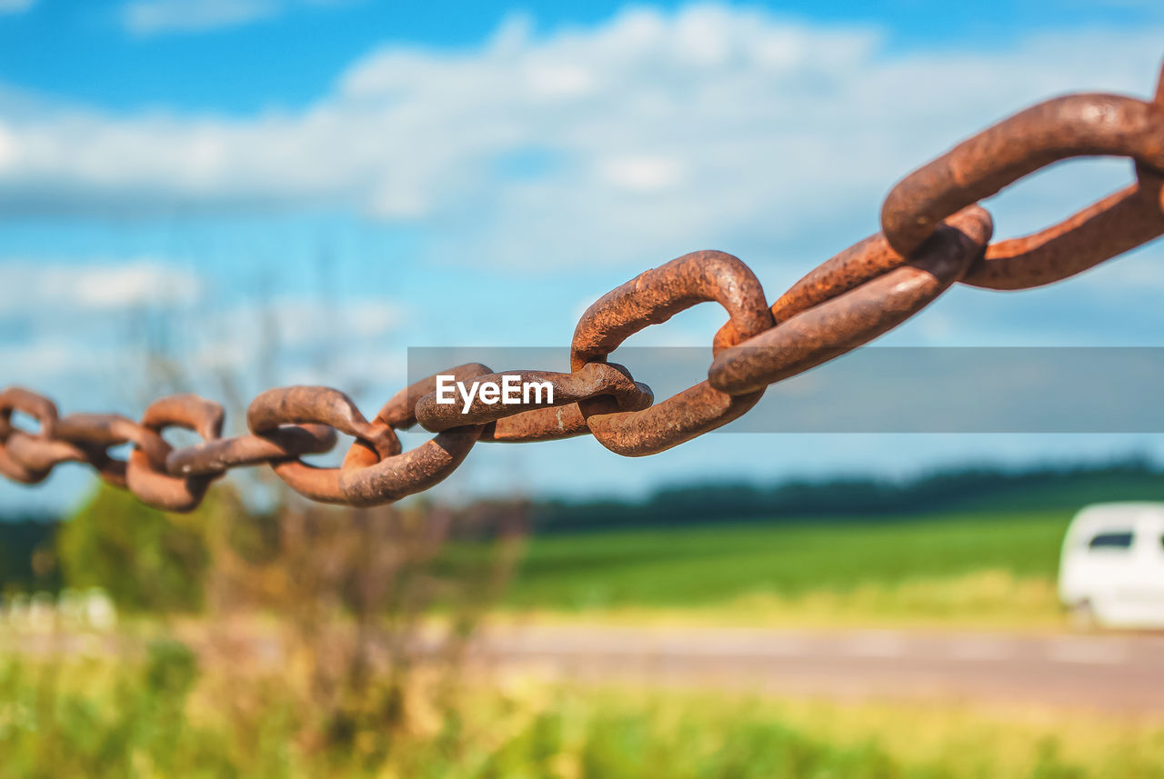 Old rusty chain on the field on background of the sky