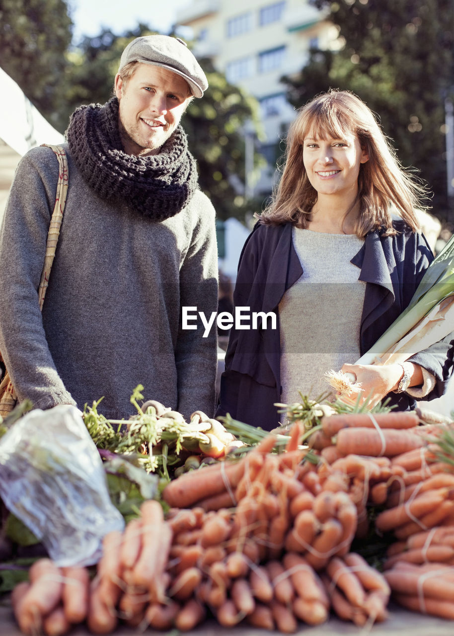 Portrait of couple buying vegetables at market