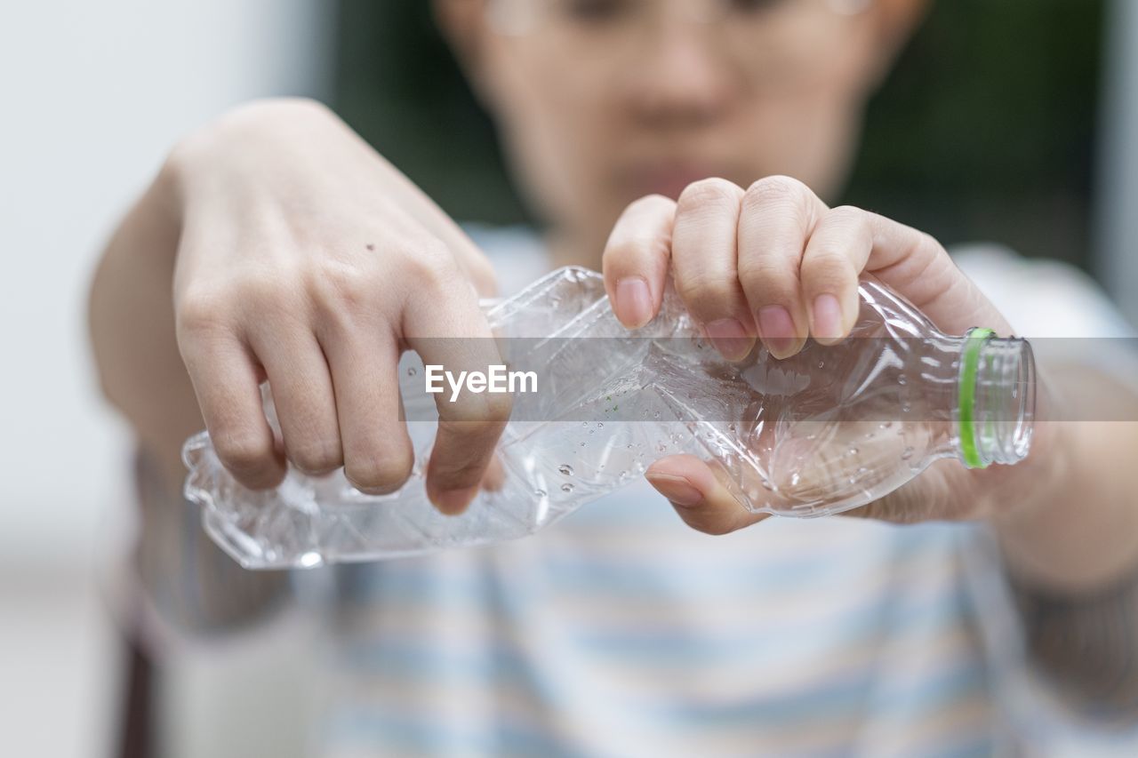 Midsection of woman crushing plastic bottle