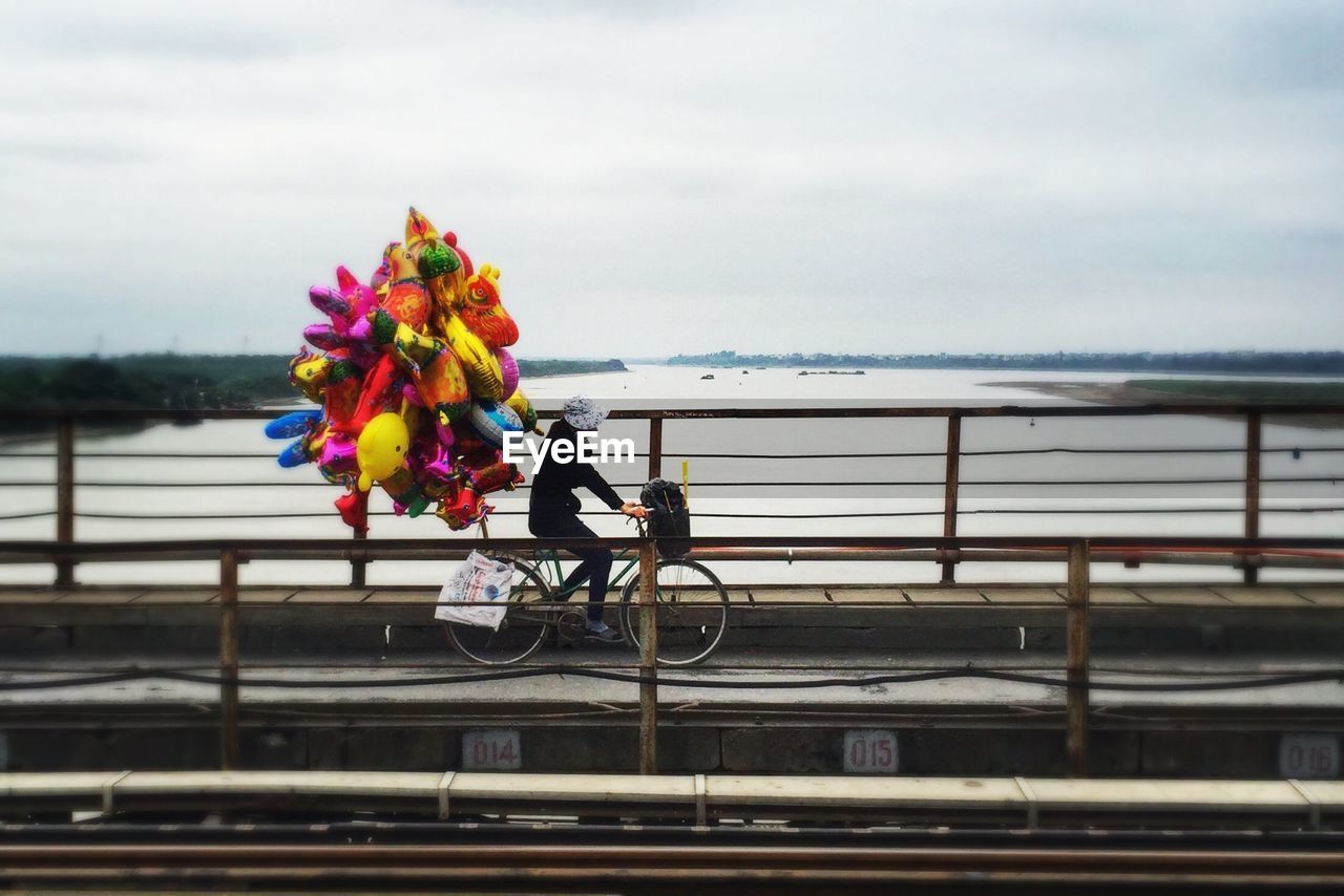 Side view of person riding bicycle with balloons