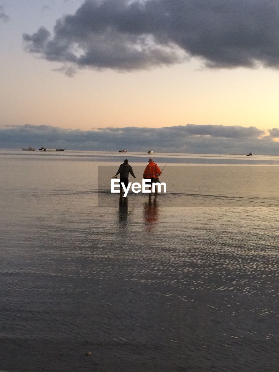 REAR VIEW OF PEOPLE ON BEACH AGAINST SKY