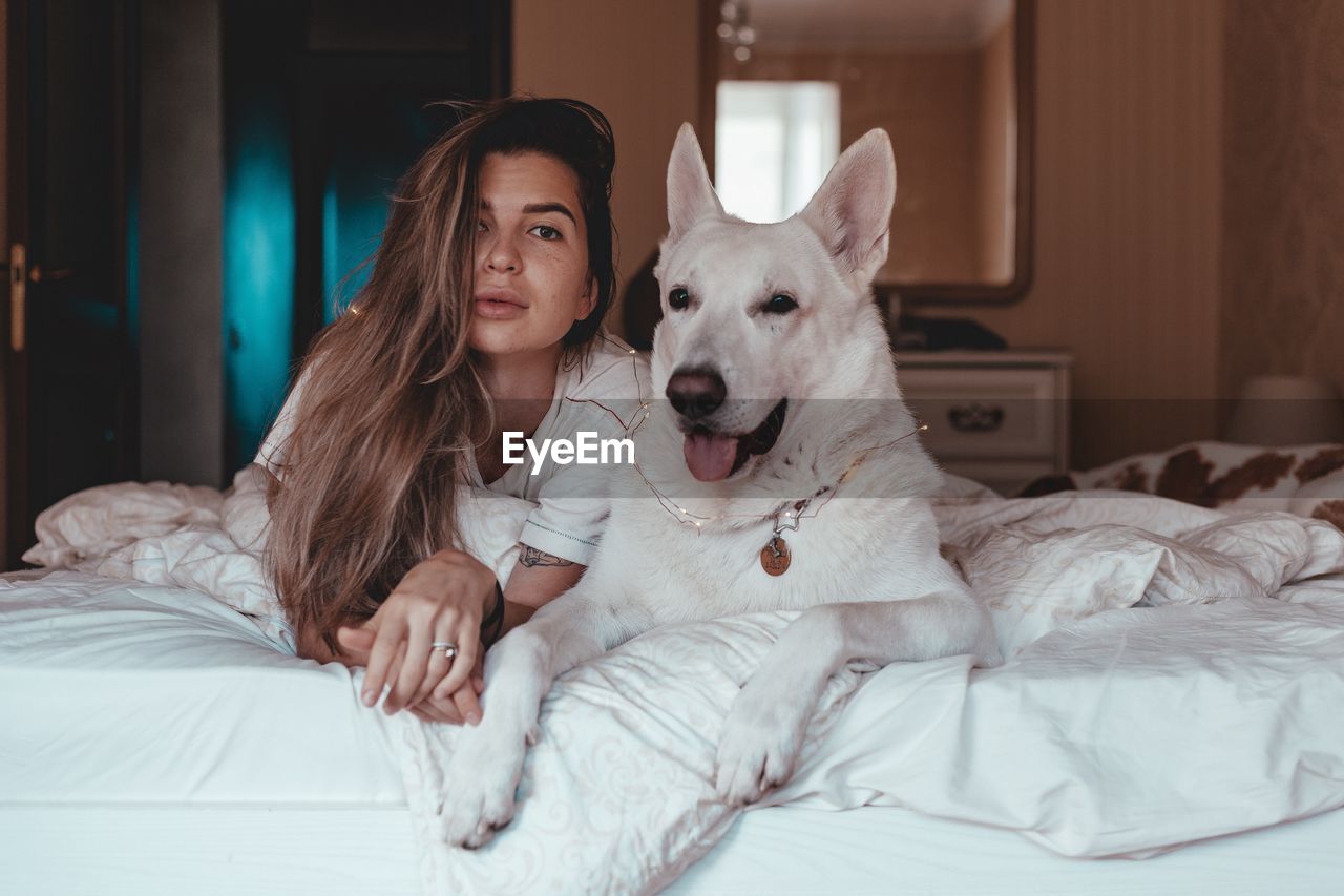 Portrait of woman with dog lying on bed at home