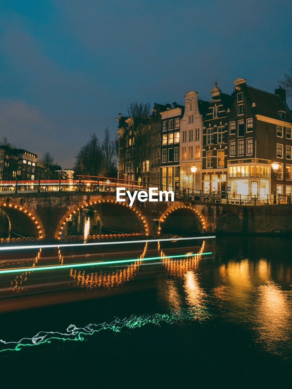 ILLUMINATED BRIDGE OVER RIVER AGAINST SKY