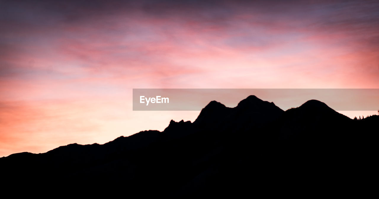 SCENIC VIEW OF SILHOUETTE MOUNTAINS AGAINST SKY AT SUNSET