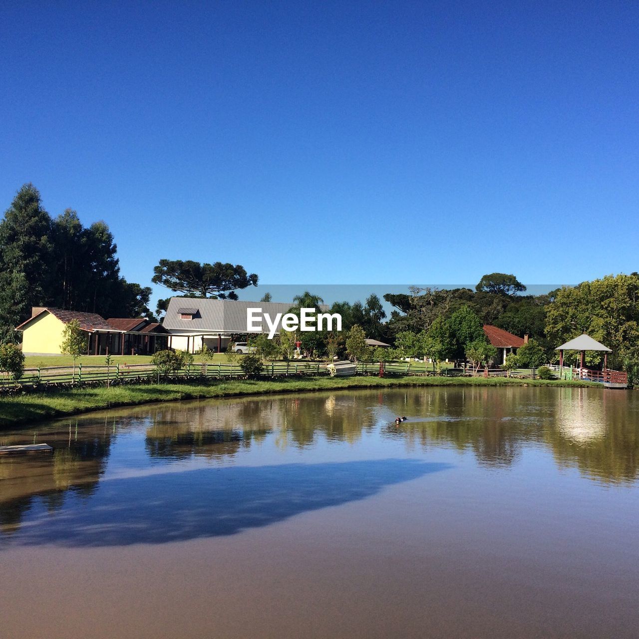 View of lake by houses against clear blue sky