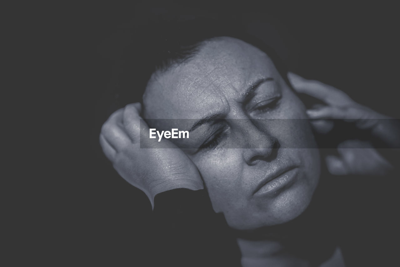 Close-up of woman against black background