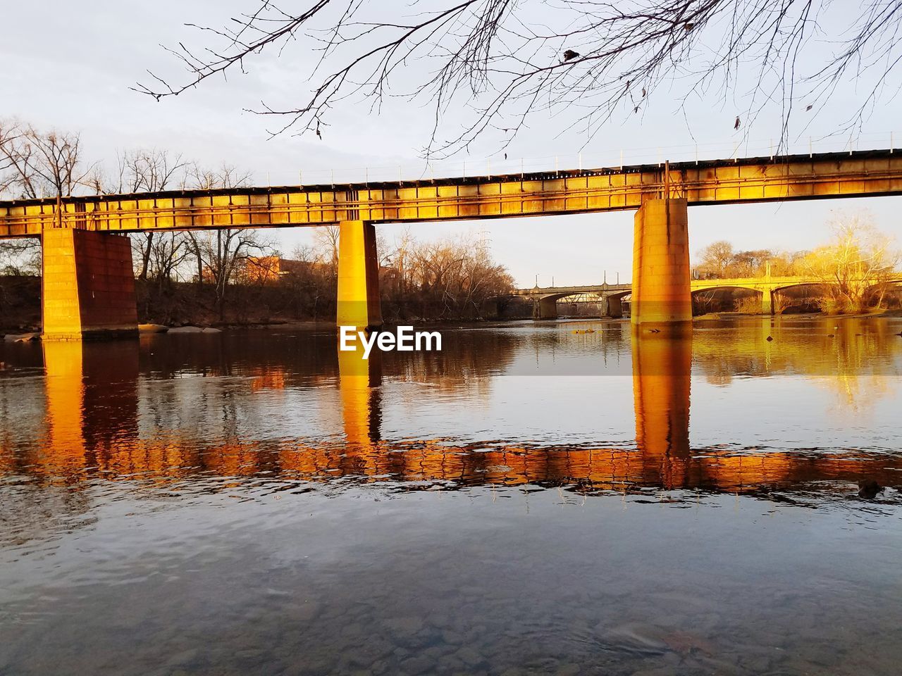 REFLECTION OF BRIDGE ON RIVER AGAINST SKY