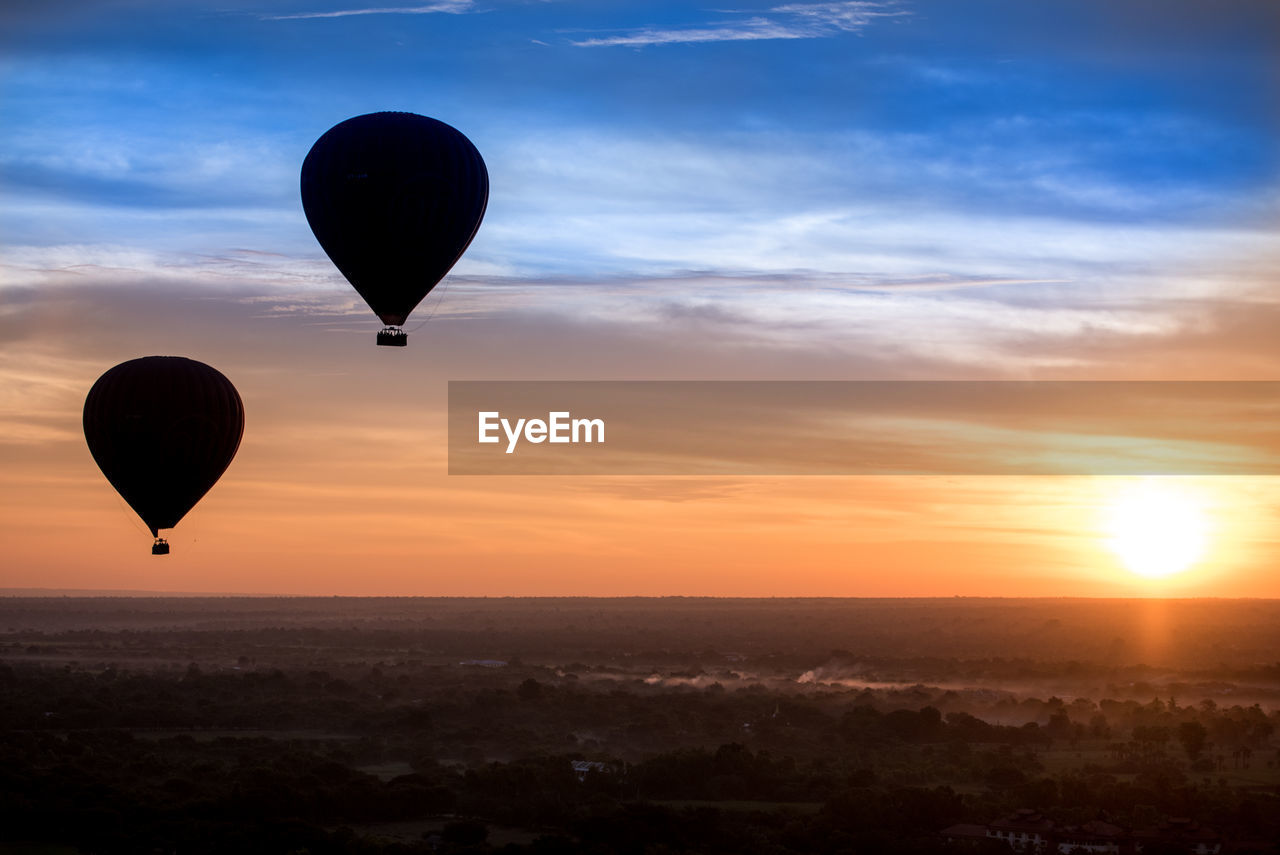HOT AIR BALLOONS FLYING AGAINST SKY DURING SUNSET