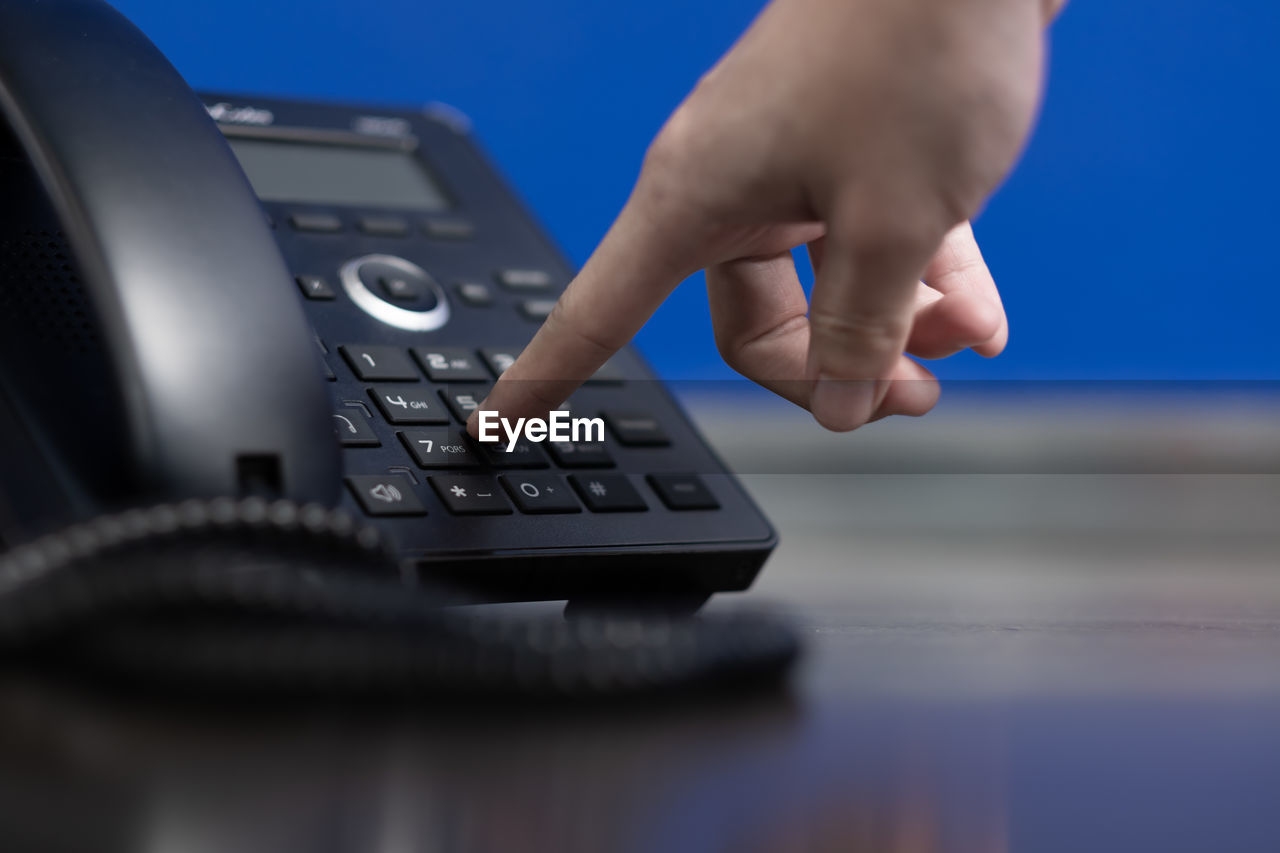 Close-up of hand using telephone on table